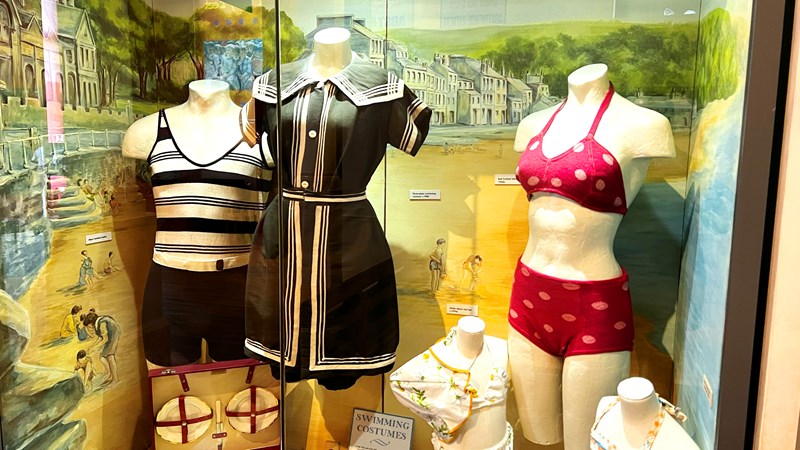 Photograph shows a range of vintage bathing costumes on display