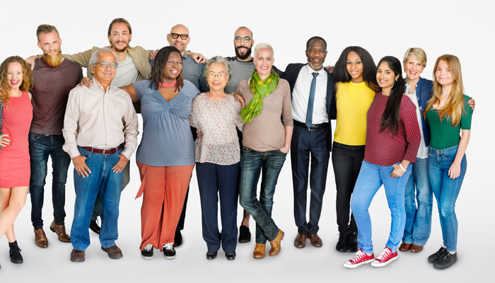 a large group of people smiling and facing the camera. They are all various ages and ethnicities.