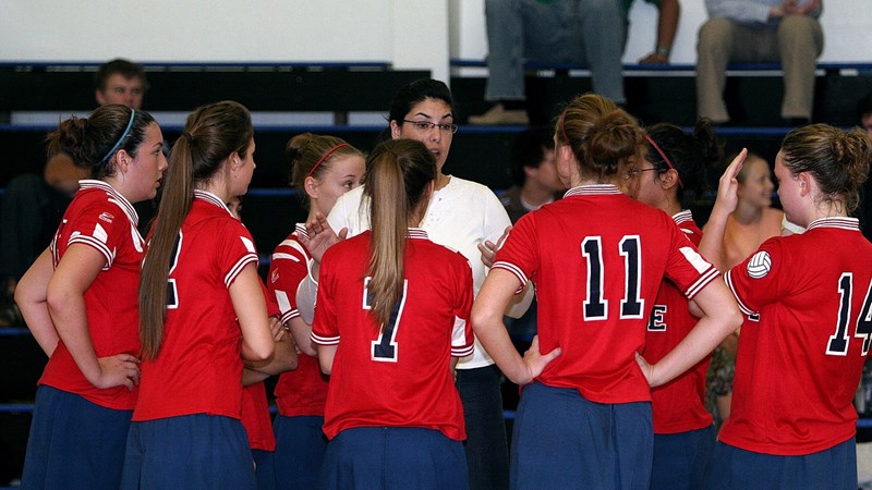 A coach talks to a group of young women, who are in a Volleyball team