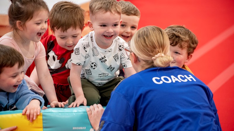 A group of children smiling and laughing at soft play