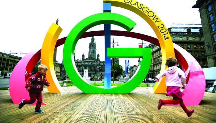 Two children running in front of the Big G sculpture in George Square during the Glasgow 2014 Commonwealth Games.