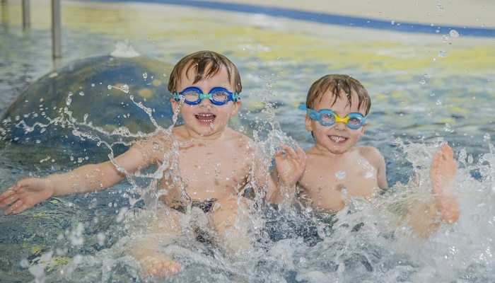 Two children smiling while playing in a swimming pool together