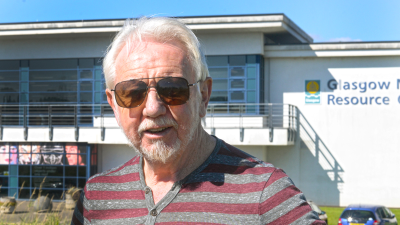 Photograph of writer Chris Dolan standing in front of Glasgow Museums Resource Centre in Nitshill