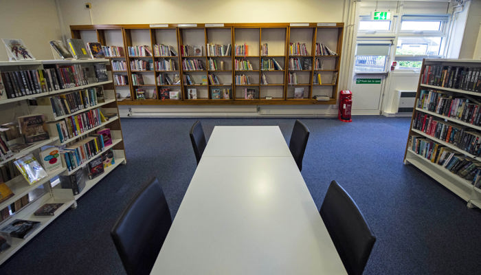 Three bookshelves surrounding a white rectangular table