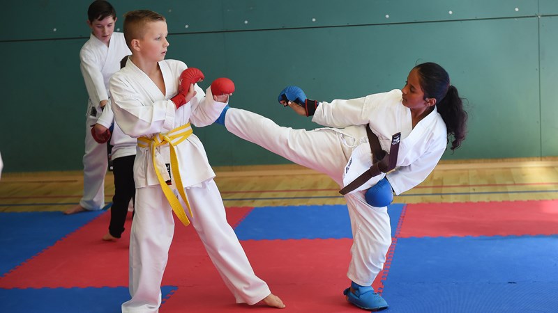 Two kids practicing a high kick 