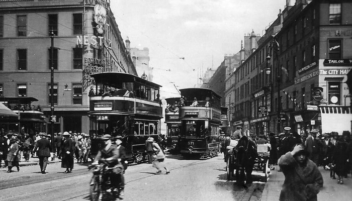 A black and white image of Glasgow from early 1900s showing a busy street with people milling around