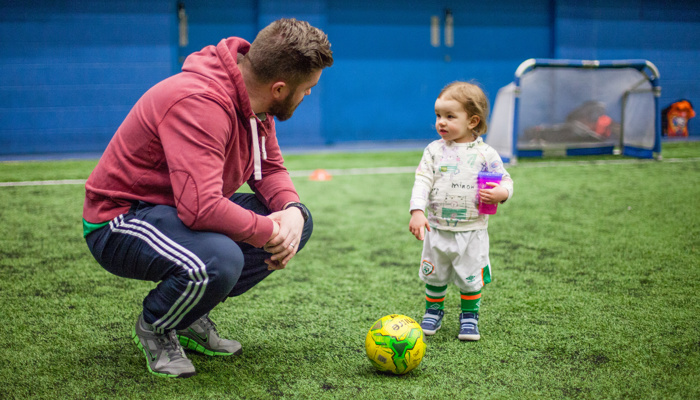 A football coach speaking to a young child during a session