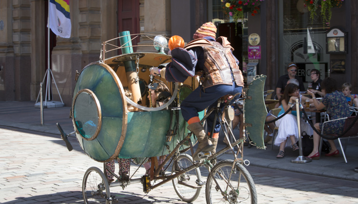 A street performer cycling through Merchant City in Glasgow on a sunny day as part of the Merchant City Festival at the 2014 Commonwealth Games.