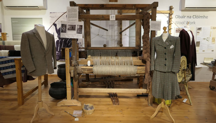 View of museum gallery showing weaving loom and tweed outfits