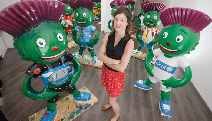 One of the artists who designed some of the Clyde mascot statues standing in the middle of a room full of Clyde statues.