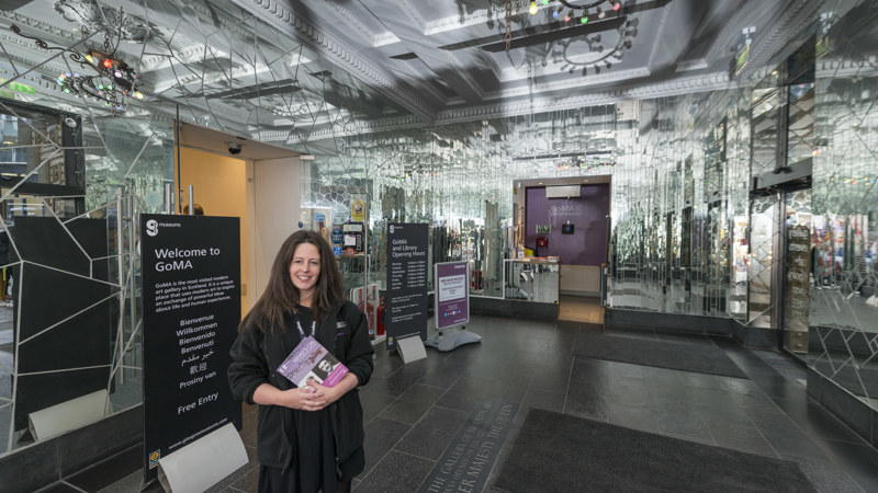 Photograph shows a gallery assistant welcoming visitors to GoMA in the entrance lobby.