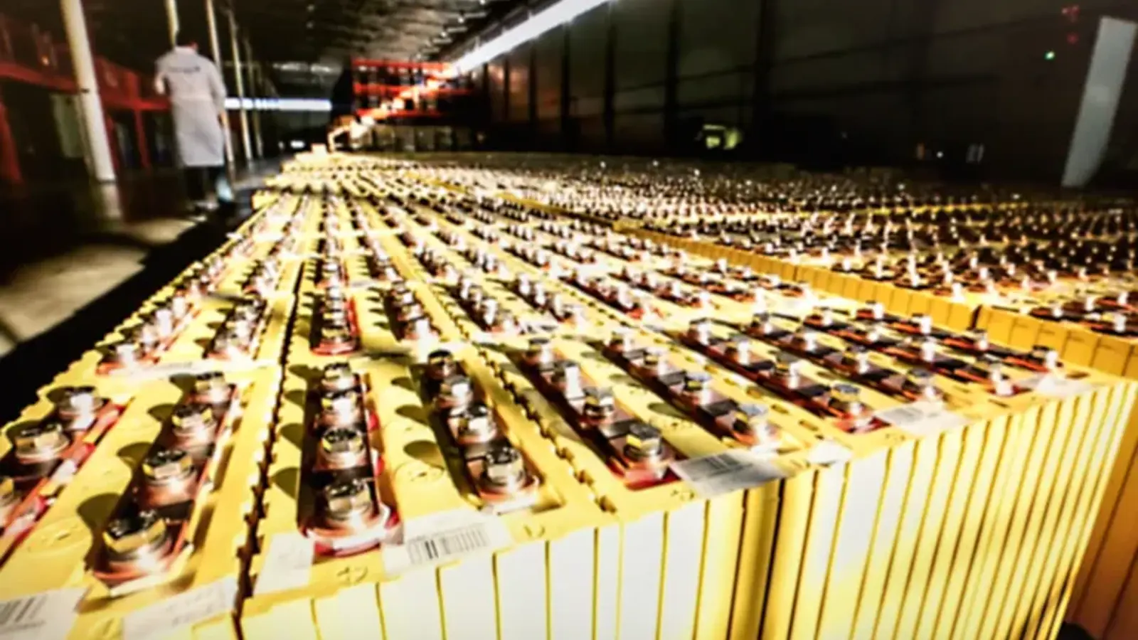 photograph of rows of yellow containers and a person in a lab coat.