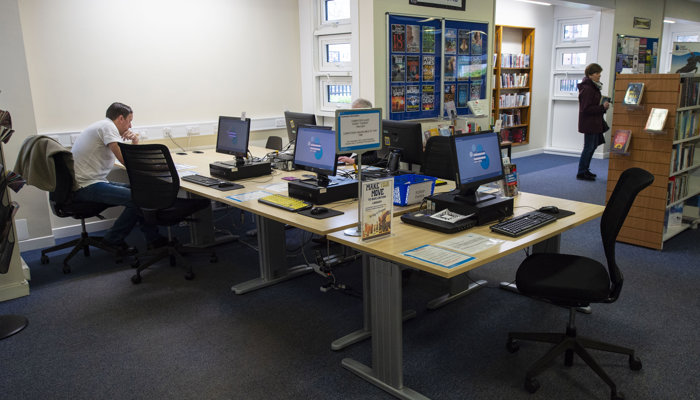 A large rectangular table with black PC's around it. 