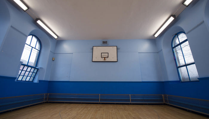 sports hall with wooden floors and blue walls. there are windows on the left and right of the room