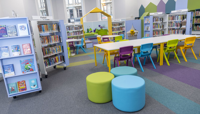 Brightly coloured children's area in Partick Library. There are round stools, coloured chairs, bright carpets and lots of books.