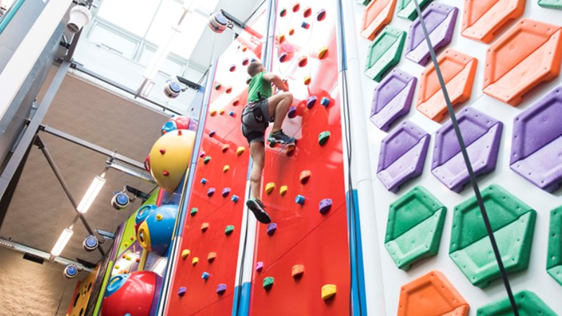 child climbing up a colourful climbing wall