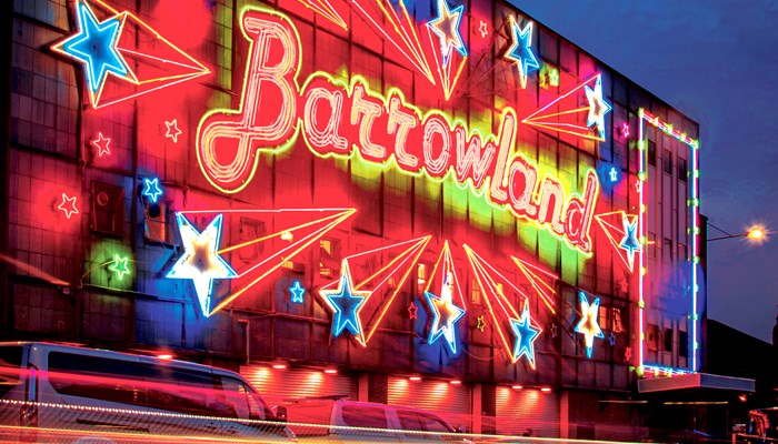External shot of the Barrowland venue at night. The name of the venue is lit up in red and yellow, with illuminated stars all around. 