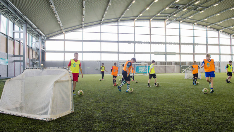 A group of children dribbling footballs while playing indoors at Toryglen