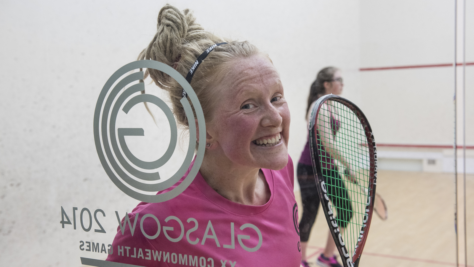 Two people playing squash at Scotstoun with one smiling at the camera.