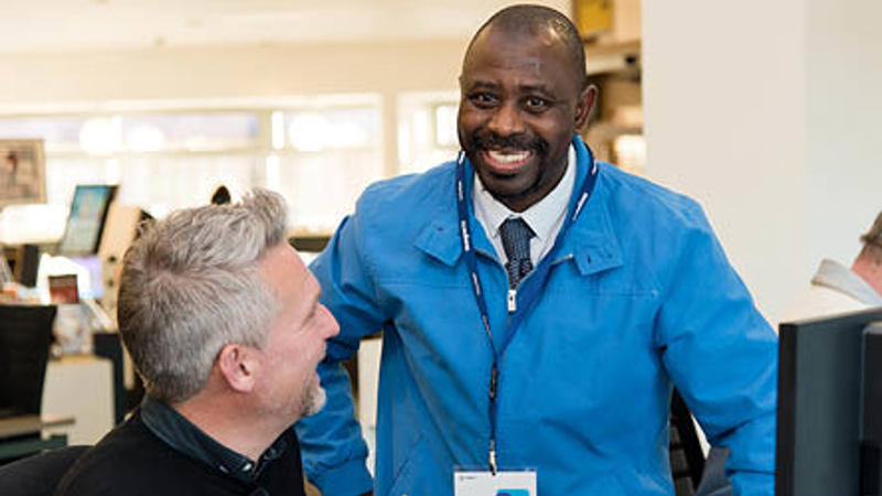 Two people are smiling looking at a computer screen