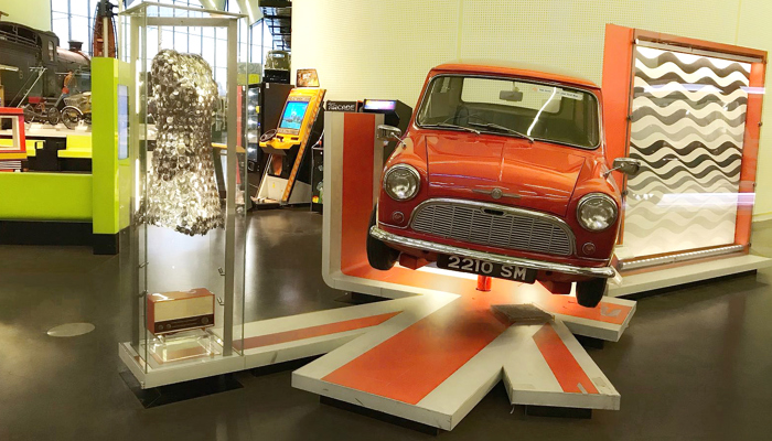 Photograph showing a dress worn by actress Audrey Hepburn on display alongside an original Mini