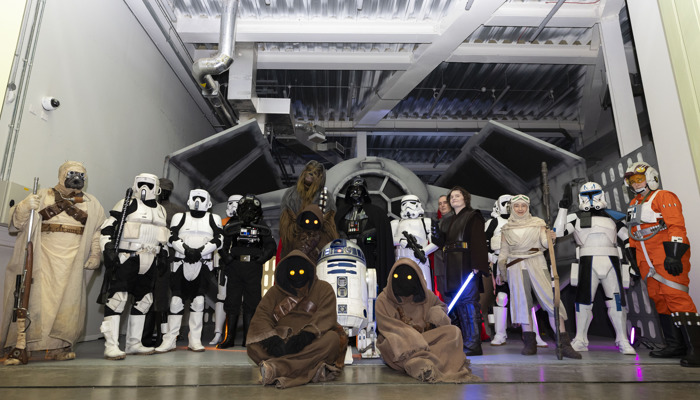 Characters from a science fiction space saga stand in front of a space speeder