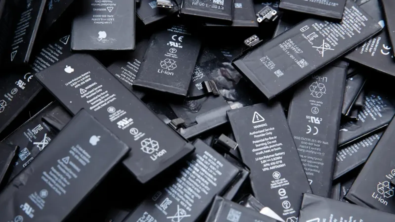 an image showing discarded black iPhone batteries in a heap