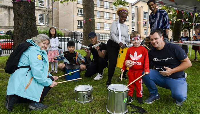 Children and adults, who represent different genders and ethnicities, trying out some musical instruments during a GO LIVE event at the UCI Cycling World Championships.