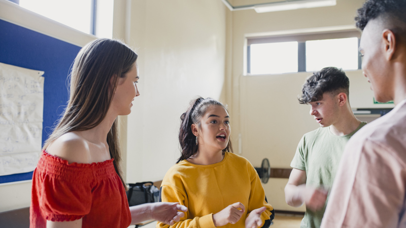 Group young people in brightly coloured clothing having an animated discussion