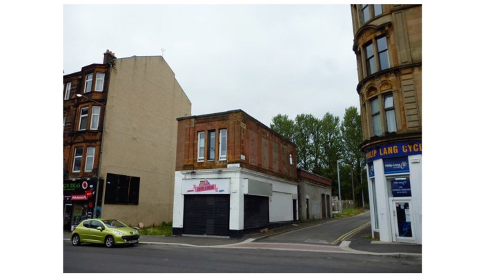 a photo of a short one-storey red sandstone commercial property and the cobbled lane beside it.