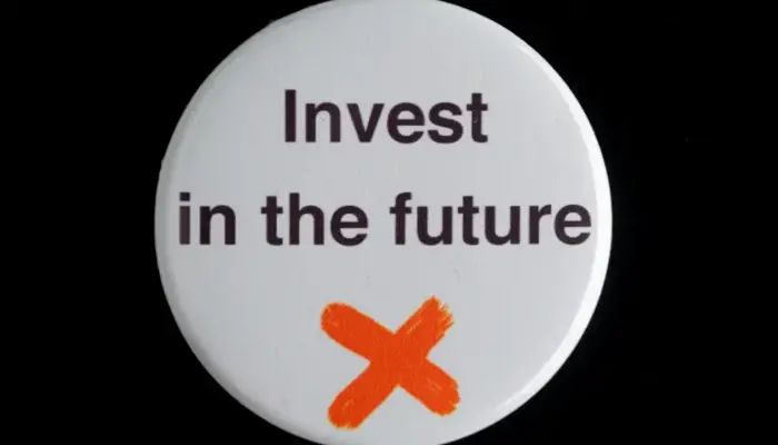 photo of a plastic badge with the words "Invest in the future" written on it.