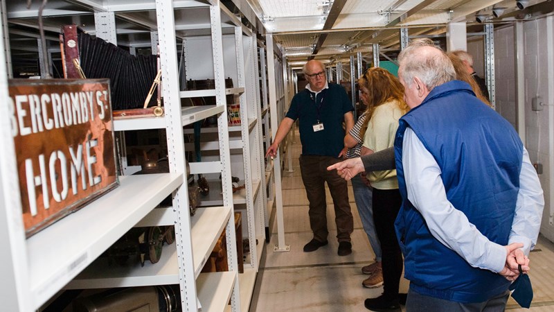 A collection of people viewing conservation items on shelves in a store room
