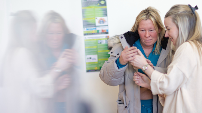 Two people standing next to each other and looking at a phone that one of them is holding