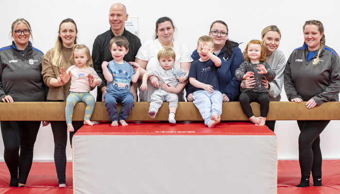 gymnastics class posing for photo on beam