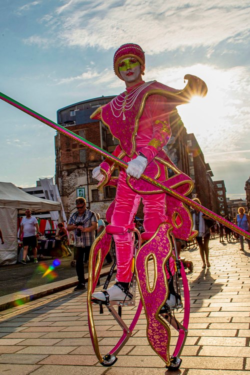 Carnival street person dressed in pink and on stilts