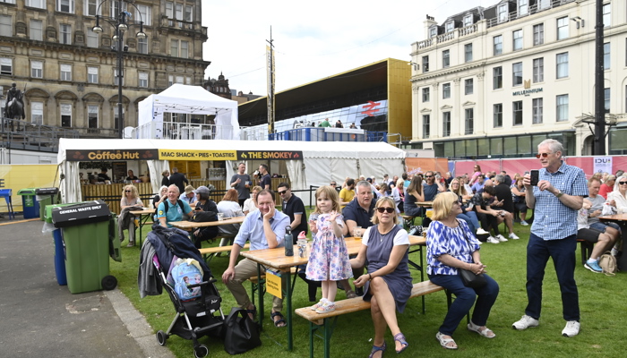 Families sitting in the George Square GO LIVE fan zone in Glasgow during the 2023 UCI Cycling World Championships.