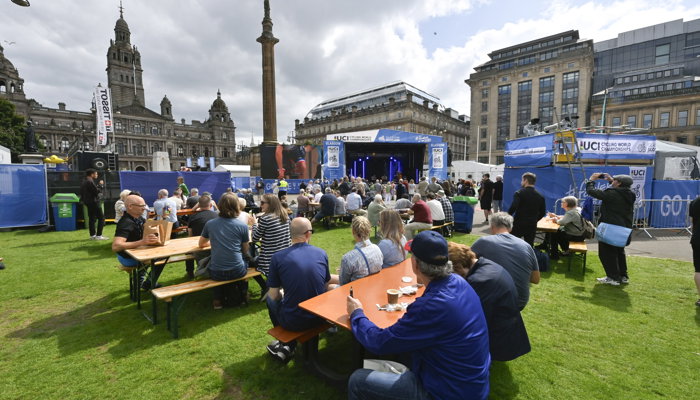 People sitting at benches and standing the George Square fan zone during the 2023 UCI Cycling World Championships.