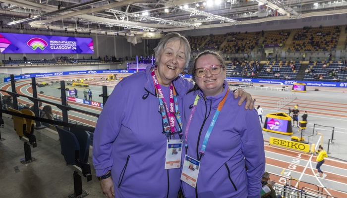 Two volunteers with their arms round each other in the stands at the Emirates Arena during the 2024 World Athletics Indoor Championships.