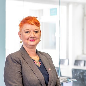 Chair of Glasgow Life board, Chair Bailie Annette Christie wearing a grey suit jacket and blue top against a bright window