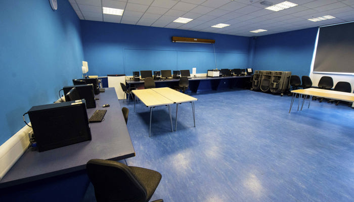 room with blue walls and a blue floor with desks and computers positioned around the room