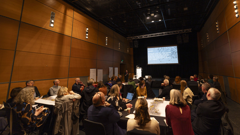 Groups of people sitting down at tables look at a PowerPoint screen during a workshop at the Centre for Contemporary Arts on Sauchiehall Street.