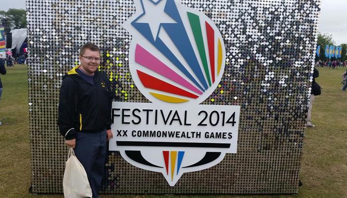 Andrew McVie in front of the shiny Festival 2014 sign at Glasgow Green during the Commonwealth Games.