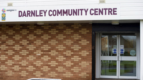 red brick wall with the words darnley community centre printed on a white sign above the door