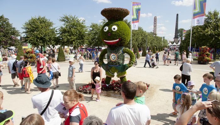 People getting their picture taken and looking at a large leaf sculpture of Clyde the mascot at Glasgow Green during the 2014 Commonwealth Games.