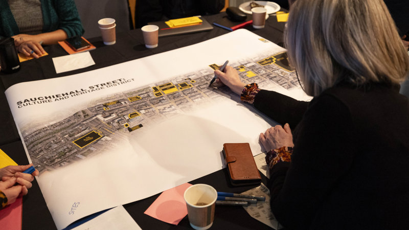 A picture of a person drawing on a map of Sauchiehall Street, taken from behind the person.