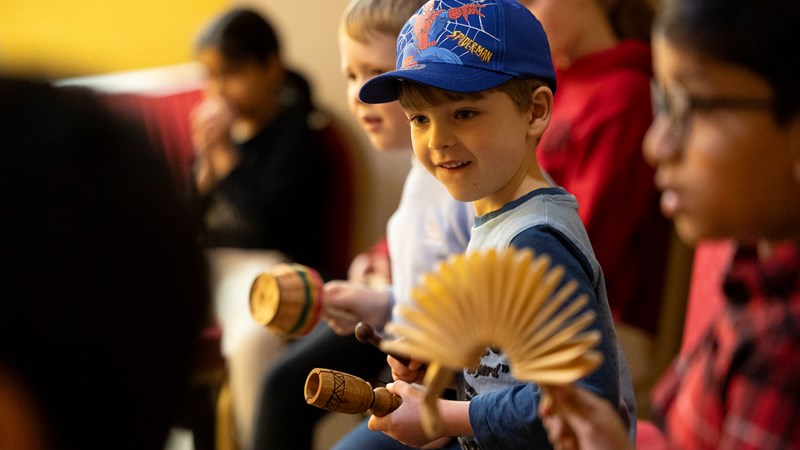 A young boy sitting amongst a group playing percussion instruments