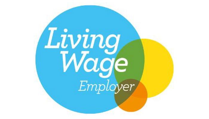 Living Wage Employer logo: A blue circle with the text "Living Wage Employer" and three overlapping coloured circles (green, yellow, and orange), with a green checkmark.