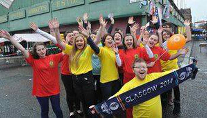 Andrew McVie holding a Glasgow 2014 scarf in front of a group of other volunteers during the Commonwealth Games.