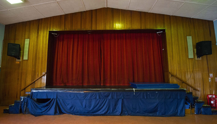 a stage with red curtains closed across it. there are stairs which lead up onto the stage from both sides