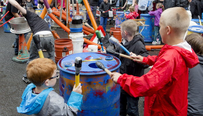 Young people playing the drums on old barrels as part of the 2014 Merchant City Festival.